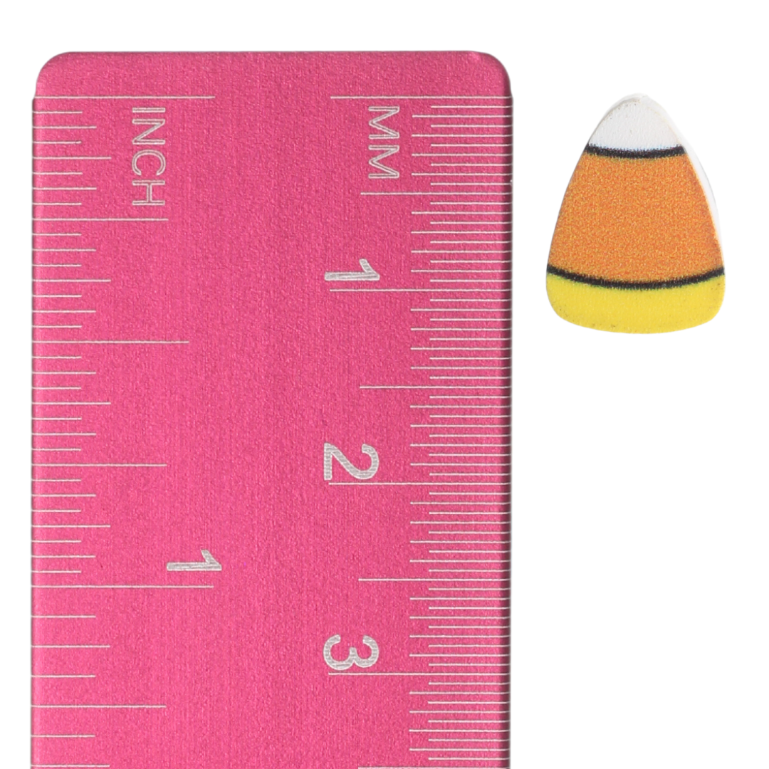 Candy corn stud earring beside an inch and centimeter ruler for size reference