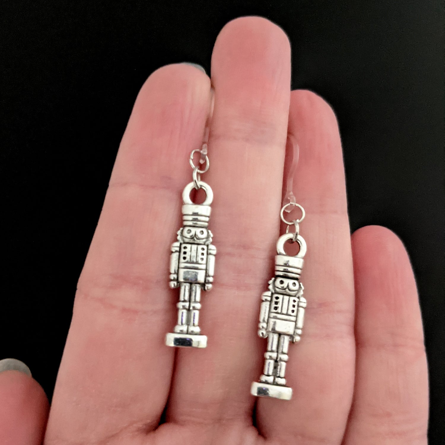 Silver Nutcracker Earrings (Dangles) - nutcracker on stand - size comparison hand