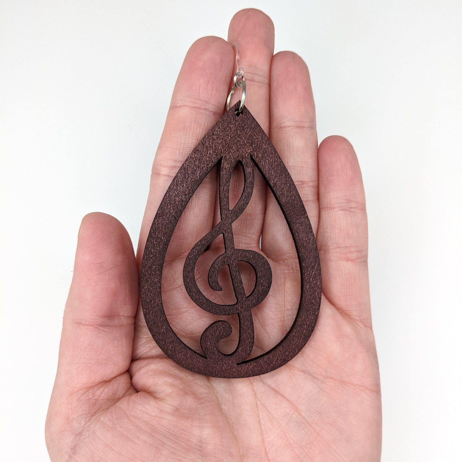Exaggerated Wooden Treble Clef Earrings (Dangles) - size comparison hand