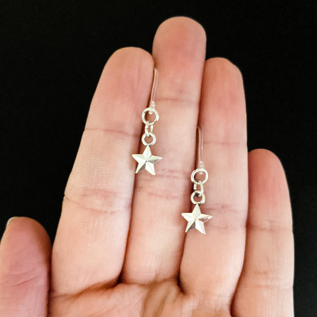 Tiny Silver Star Earrings (Dangles) - size comparison hand